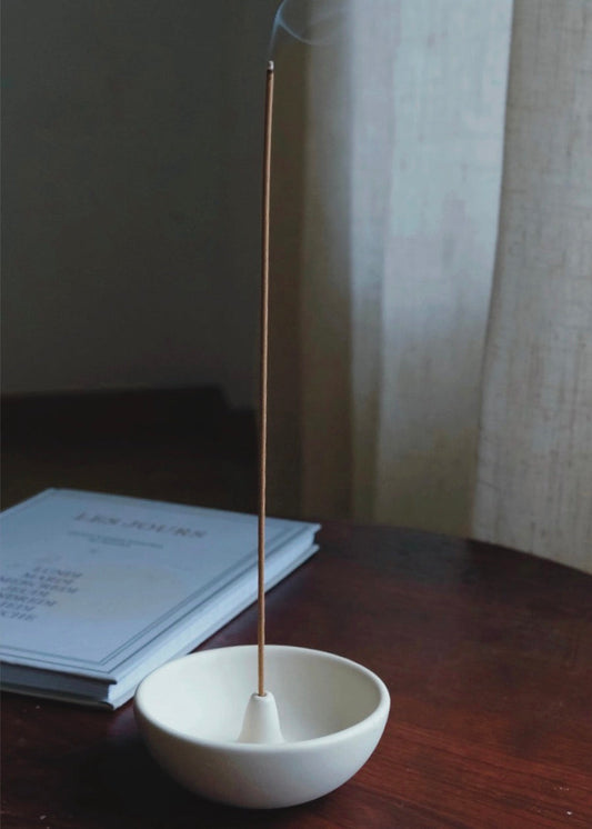 porte encens minimaliste blanc avec encens fumant près d’une fenêtre lumière douce