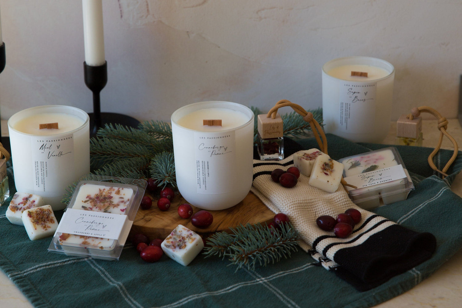 Mise en scène de la collection hivernale Les Passionnées avec chandelles parfumées, cubes de cire et accessoires créant une ambiance chaleureuse et réconfortante