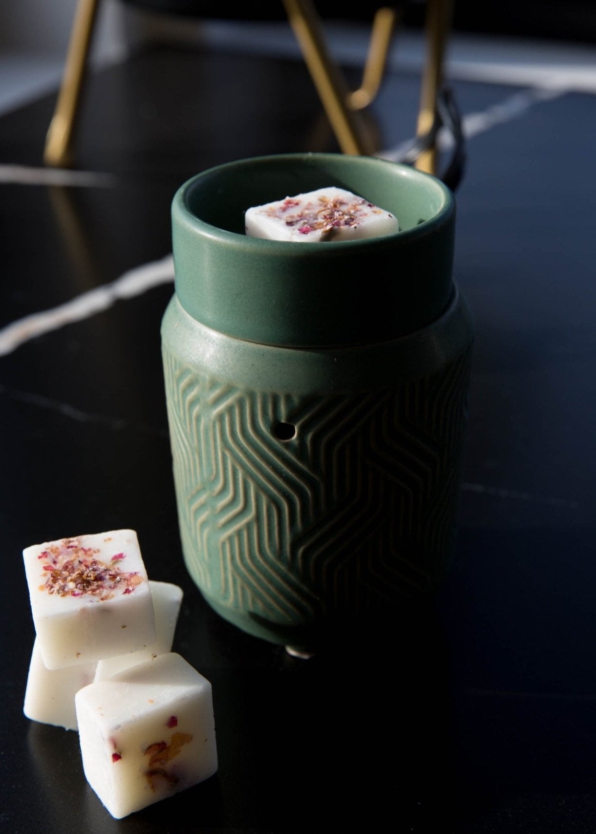 Brûleur de cubes de cire sur table Jade en céramique verte avec cubes de cire parfumés, posé sur une surface intérieure