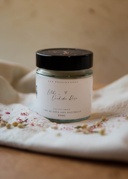 Chandelle parfumee a meche de coton litchi et orchidee rose sur tissu fleuri ambiance printaniere