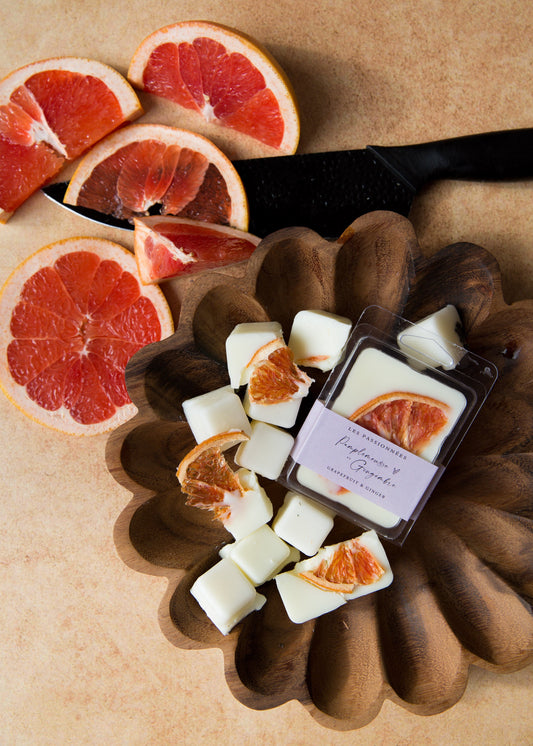 Cubes de cire parfumée pamplemousse et gingembre avec quartiers de pamplemousse sur fond beige