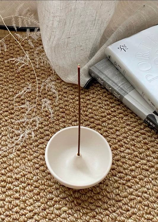 porte encens céramique blanc avec bâton encens décor naturel tapis et livre ambiance zen