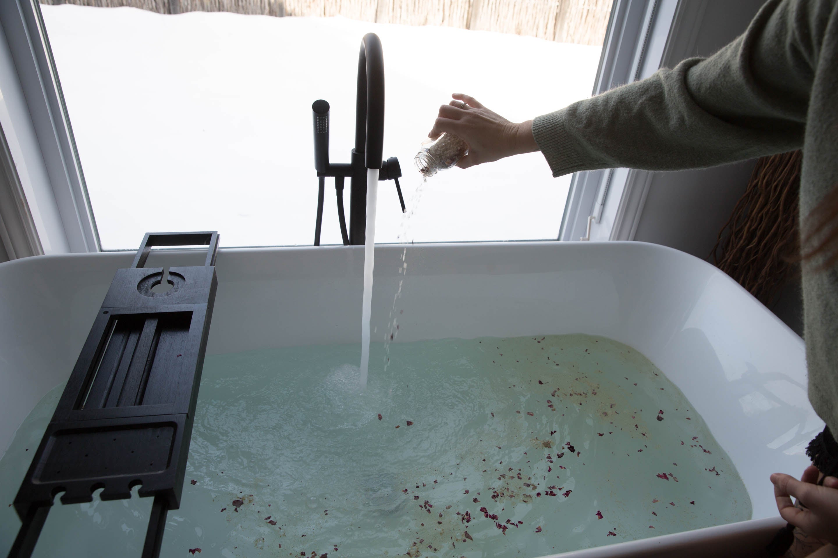 Main versant du sel de bain Les Passionnées dans une baignoire remplie d’eau chaude pour créer un rituel bien-être à la maison